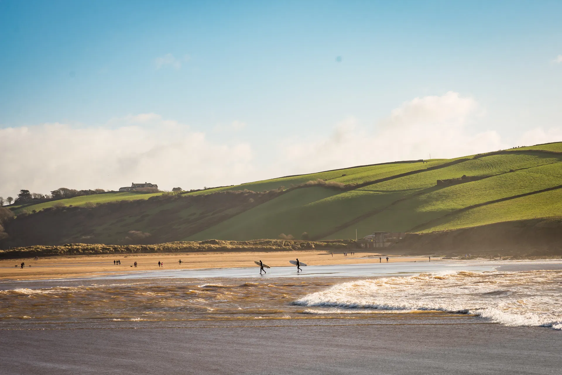 Surfers walking along Bantham Beach with boards