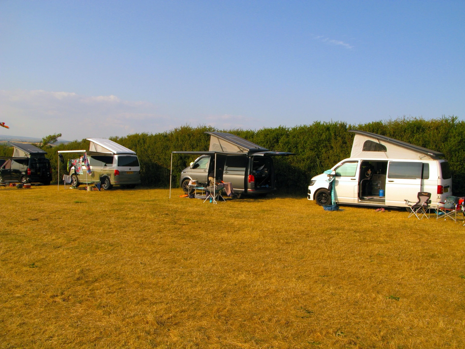 Campervans with awnings and solar panels pitched in a row